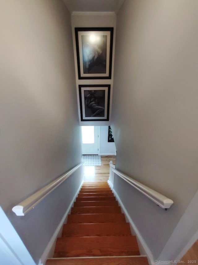 staircase featuring crown molding, baseboards, and wood finished floors