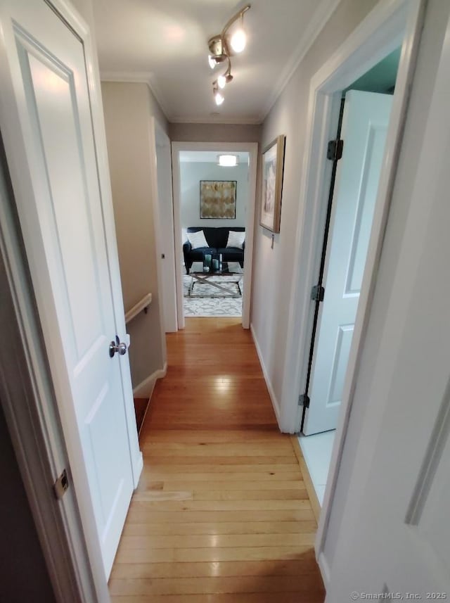corridor featuring ornamental molding, light wood-style flooring, and baseboards