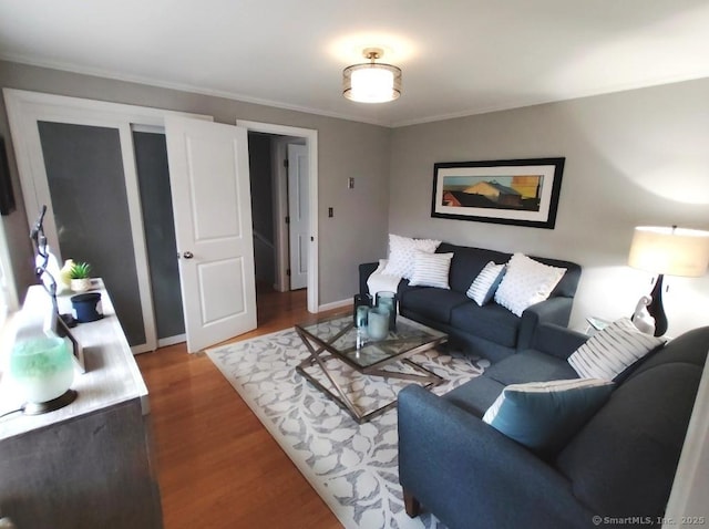 living area with baseboards, ornamental molding, and wood finished floors