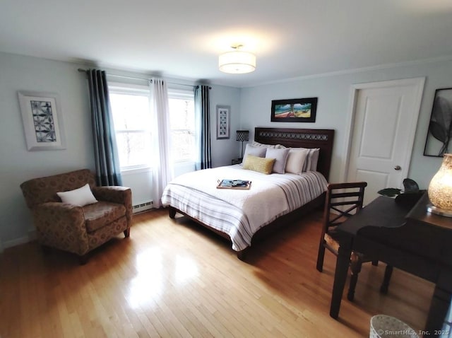 bedroom featuring light wood finished floors and a baseboard heating unit