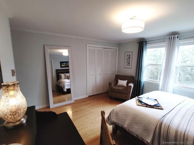 bedroom with a closet, light wood-style flooring, baseboards, and crown molding