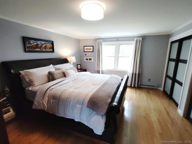 bedroom featuring light wood-style flooring and a baseboard radiator