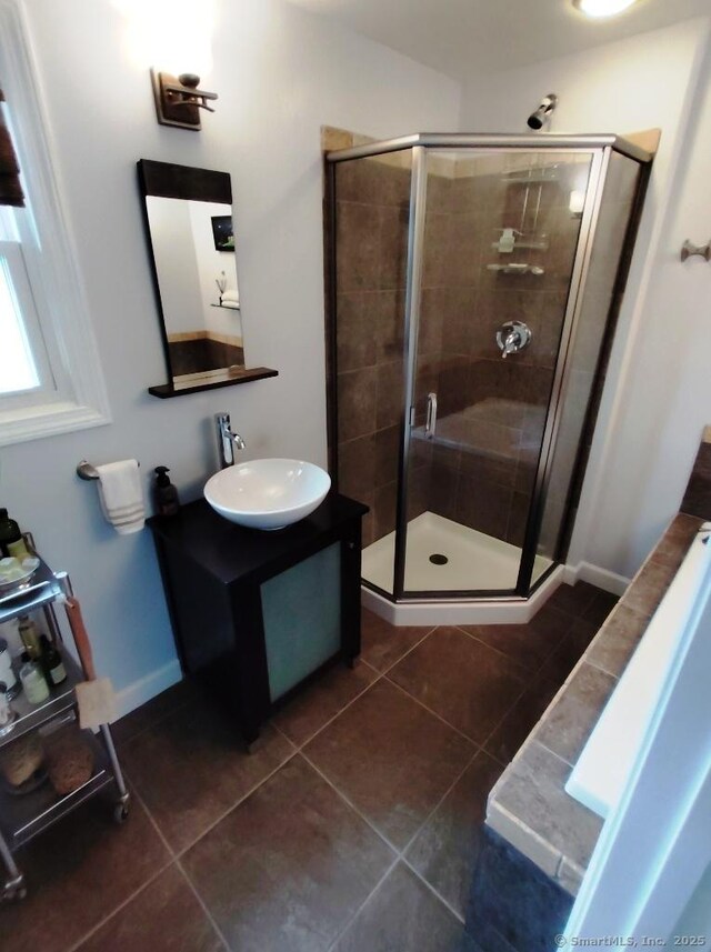 bathroom featuring tile patterned floors, a stall shower, baseboards, and vanity