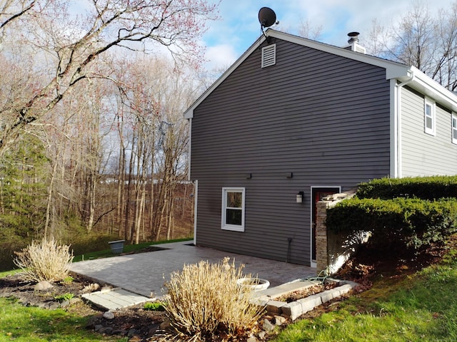 view of property exterior featuring a patio and a chimney