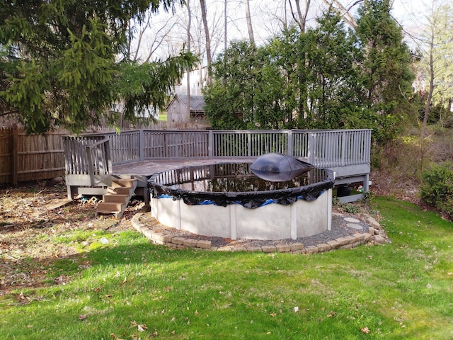 view of swimming pool featuring a yard, a wooden deck, fence, and a covered pool