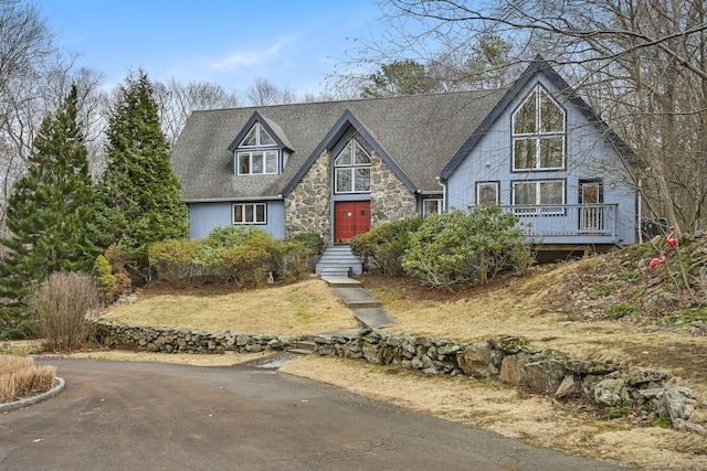 view of front facade with roof with shingles and stone siding