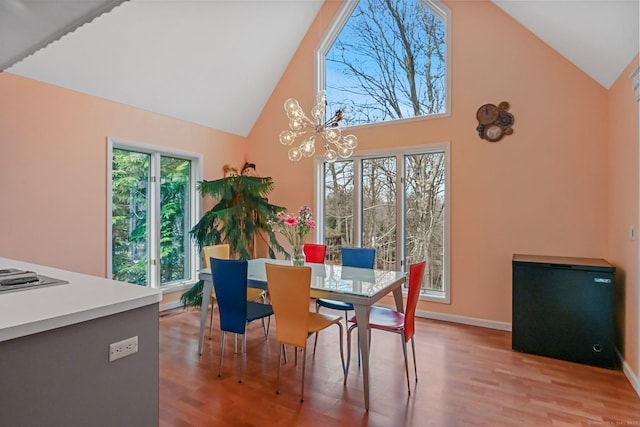 dining room with high vaulted ceiling, baseboards, light wood-type flooring, and a chandelier
