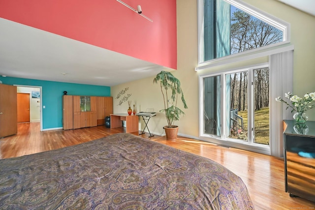 bedroom featuring visible vents, a high ceiling, baseboards, and wood finished floors