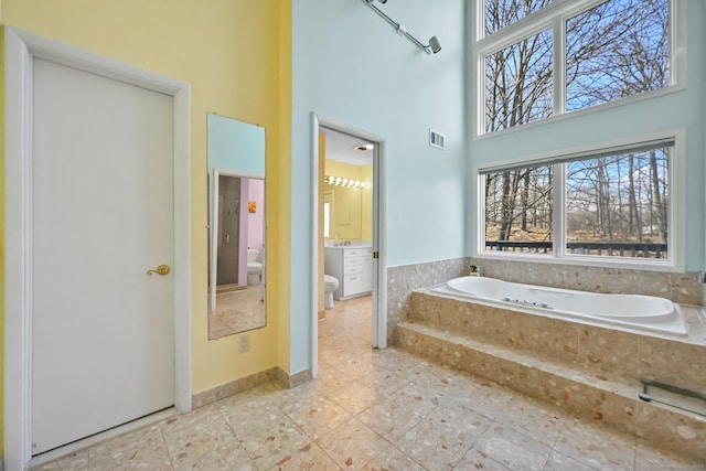 bathroom with visible vents, tile patterned flooring, a towering ceiling, toilet, and a bath
