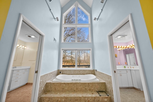 full bathroom with visible vents, a healthy amount of sunlight, a bath, and vanity