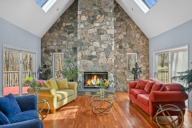 living area featuring high vaulted ceiling, wood finished floors, a skylight, and a fireplace
