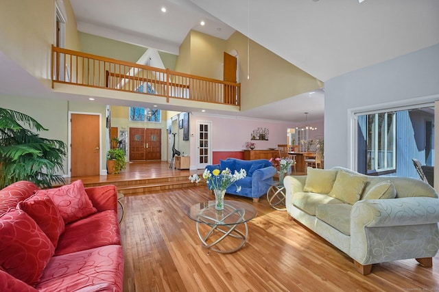 living area with recessed lighting, high vaulted ceiling, an inviting chandelier, and wood finished floors