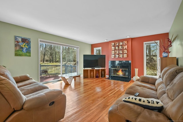 living room featuring a fireplace with flush hearth and light wood-style flooring