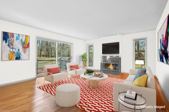 living area featuring baseboards, wood finished floors, and a high end fireplace