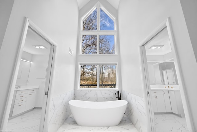 bathroom with marble finish floor, two vanities, and wainscoting