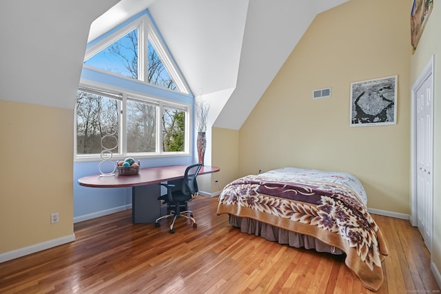 bedroom with baseboards, vaulted ceiling, hardwood / wood-style flooring, and visible vents