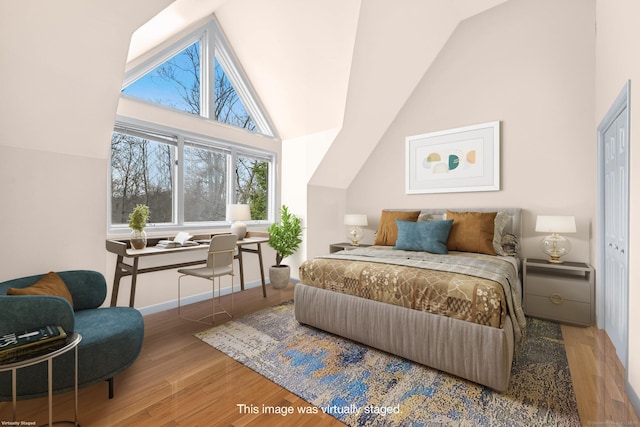 bedroom with baseboards, wood finished floors, and lofted ceiling