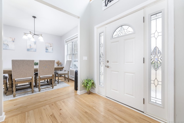 foyer with baseboards, wood finished floors, an inviting chandelier, and a baseboard radiator