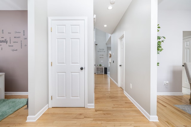 hall featuring lofted ceiling, baseboards, light wood finished floors, and recessed lighting