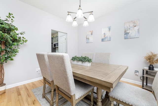 dining space featuring baseboards, a chandelier, and light wood-style floors
