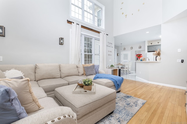 living area featuring baseboards, a high ceiling, and hardwood / wood-style flooring