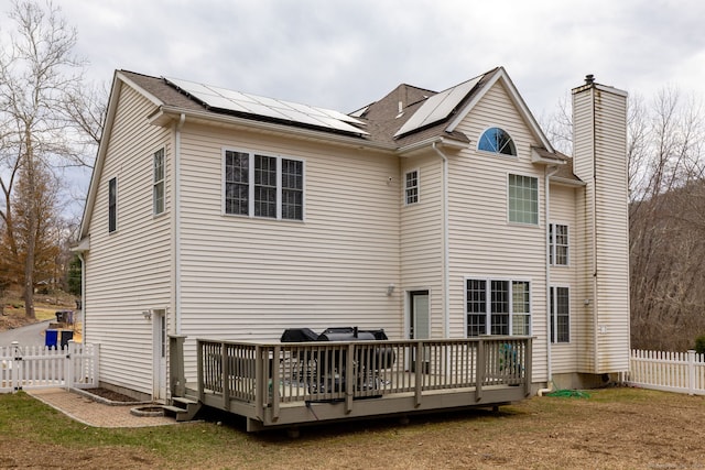 13 Sunset Ln, New Milford, CT 06776 - rear view of property featuring a chimney, a deck, solar panels, a fenced backyard, and roof with shingles