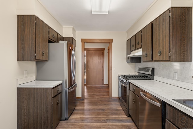 kitchen with under cabinet range hood, stainless steel appliances, dark brown cabinets, and light countertops