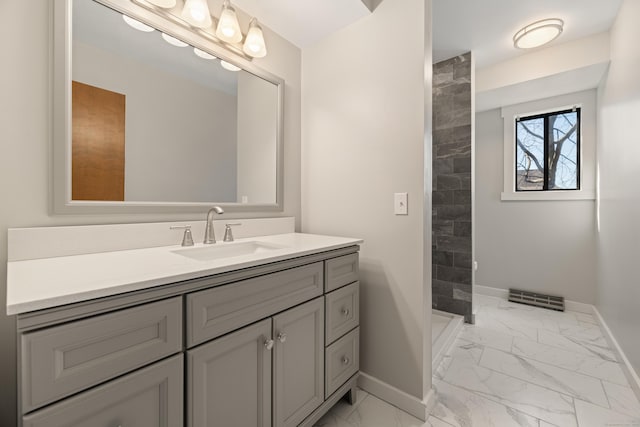 full bathroom with tiled shower, baseboards, marble finish floor, and vanity