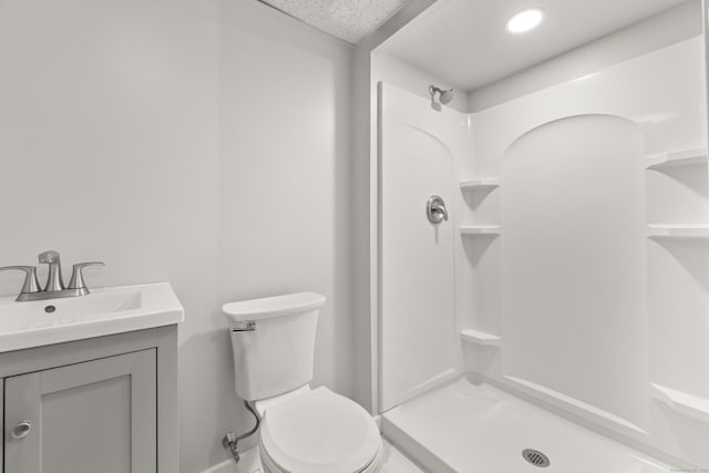 bathroom with toilet, vanity, a shower, and baseboards
