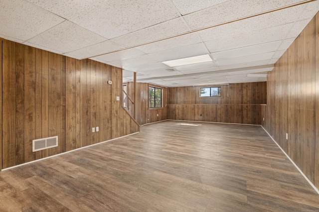 basement with visible vents, wooden walls, wood finished floors, and stairs
