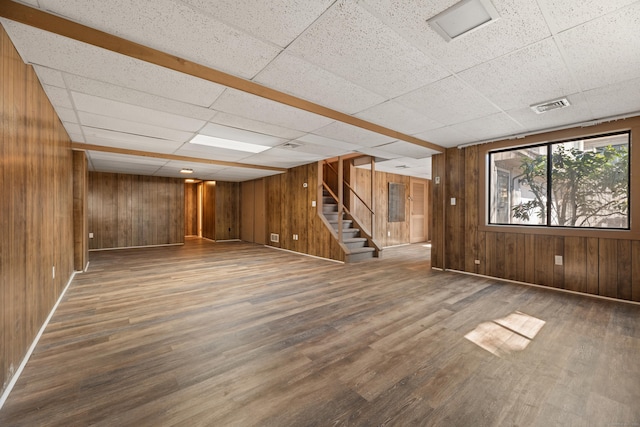 basement featuring visible vents, wood finished floors, wood walls, and stairway