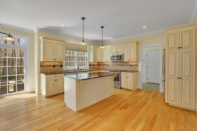 kitchen with cream cabinets, a wealth of natural light, appliances with stainless steel finishes, and light wood-type flooring