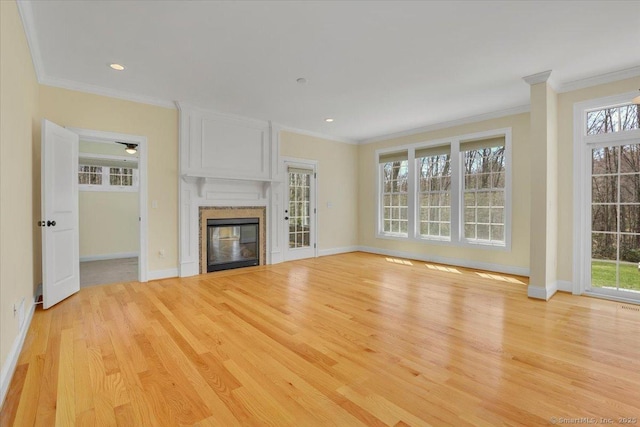 unfurnished living room with baseboards, ornamental molding, light wood-style floors, and plenty of natural light