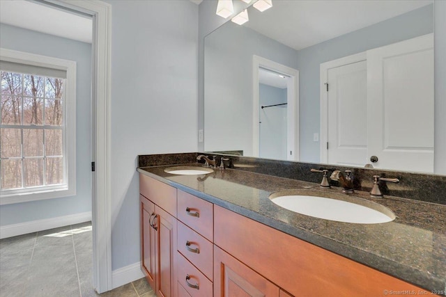 full bath with baseboards, a sink, and plenty of natural light