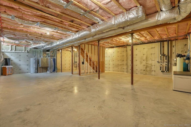 unfinished basement with electric water heater, water heater, and stairs