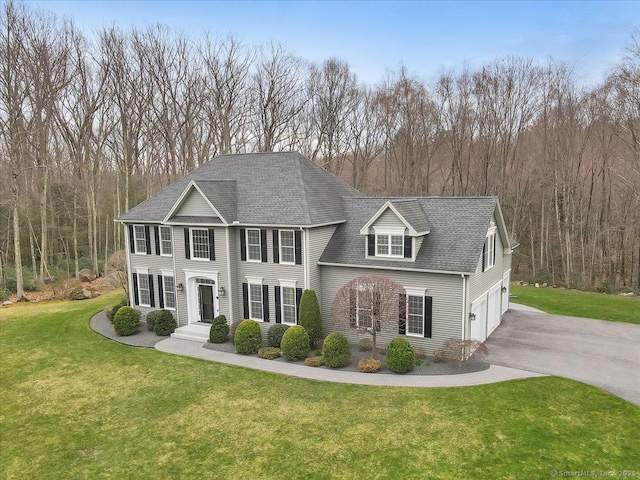 view of front of property featuring a front lawn, driveway, roof with shingles, and a garage