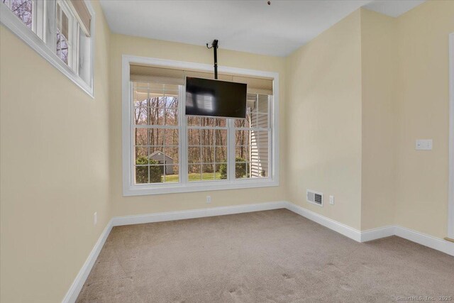 unfurnished dining area with carpet floors, visible vents, and baseboards