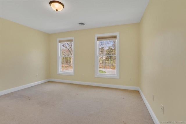 unfurnished room with baseboards, light carpet, and visible vents