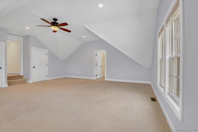 additional living space featuring carpet flooring, vaulted ceiling, baseboards, visible vents, and ceiling fan