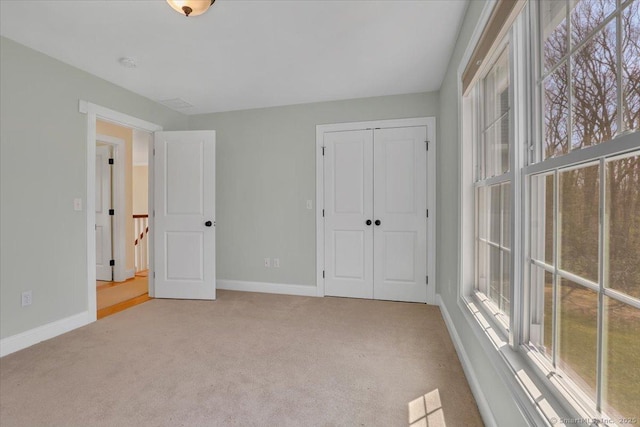 unfurnished bedroom featuring baseboards, carpet, and a closet