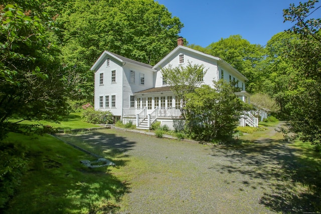 11 Hodge Rd, Roxbury, CT 06783 - back of property with stairway, a chimney, a lawn, and a porch