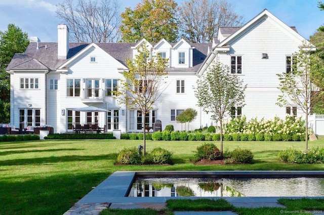 back of property featuring a lawn and a chimney