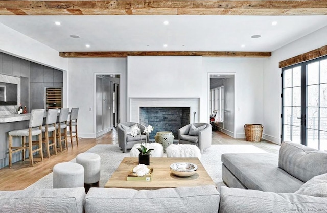 living room with beamed ceiling, light wood finished floors, a fireplace, baseboards, and recessed lighting