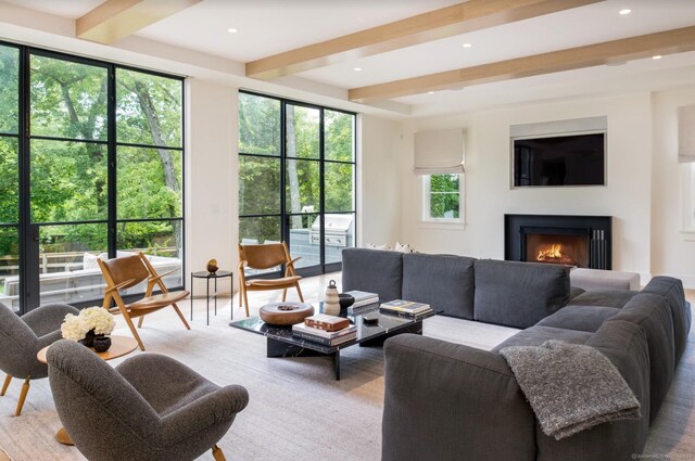 living area featuring beam ceiling, a warm lit fireplace, and recessed lighting