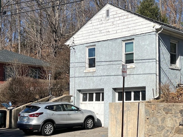 241 Harwinton Ave, Torrington, CT 06790 - view of side of home featuring stucco siding, a garage, and driveway