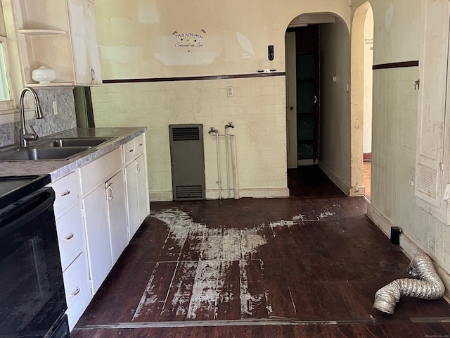 241 Harwinton Ave, Torrington, CT 06790 - kitchen featuring a sink, tile walls, white cabinets, arched walkways, and wainscoting