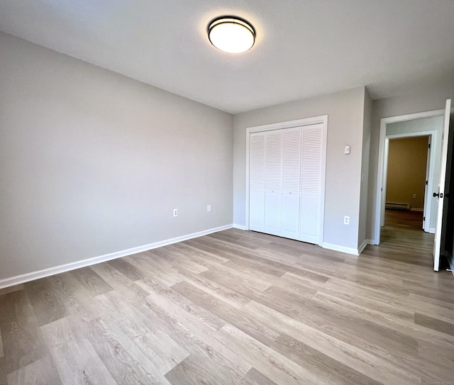 200 Yale St Unit 15B, Waterbury, CT 06704 - unfurnished bedroom with a baseboard heating unit, baseboards, a closet, and light wood finished floors