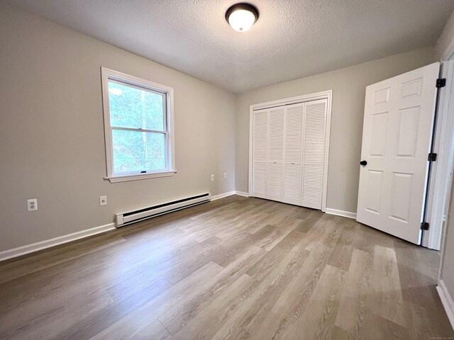 200 Yale St Unit 15B, Waterbury, CT 06704 - unfurnished bedroom with a baseboard heating unit, baseboards, wood finished floors, a closet, and a textured ceiling