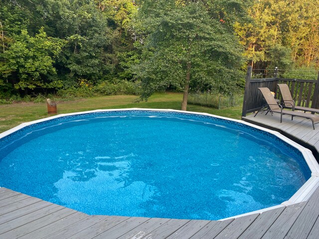 outdoor pool with a yard and a deck