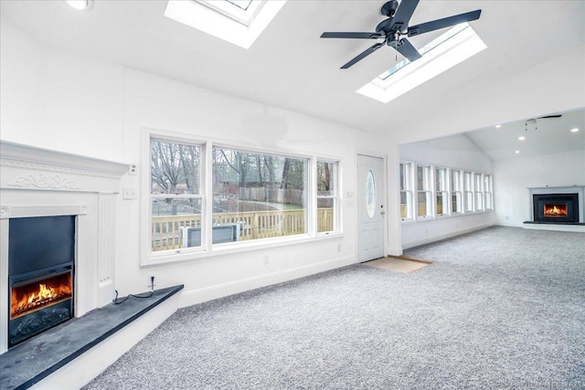 25 Jefferson Dr, New Milford, CT 06776 - unfurnished living room featuring carpet floors, baseboards, a lit fireplace, vaulted ceiling with skylight, and ceiling fan